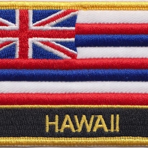 Peut inclure: Écusson brodé avec le drapeau d'Hawaï. Le drapeau présente huit bandes horizontales de rouge, blanc et bleu, avec un Union Jack dans le coin supérieur gauche. Le mot "HAWAII" est brodé en or sur un fond noir en bas de l'écusson.