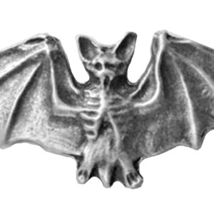 May include: A silver-coloured pewter bat figurine with outstretched wings. The bat has a detailed, skeletal-like body and a pointed snout.