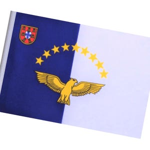 Könnte beinhalten: Eine rechteckige Flagge mit einer vertikal geteilten blauen und weißen Gestaltung. Die blaue Seite zeigt ein Wappen und einen goldenen Adler. Eine Reihe gelber Sterne verläuft über die weiße Seite. Wahrscheinlich ein regionales oder nationales Symbol.