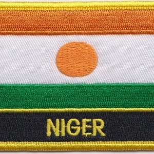Op de afbeelding: Een geborduurde patch met de vlag van Niger. De vlag is oranje, wit met een grote oranje cirkel in het midden, groen en zwart met het woord "NIGER" in gele letters.