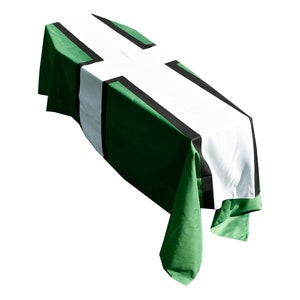 Peut inclure: Un cercueil vert, blanc et noir drapé dans un tissu à motif de croix.