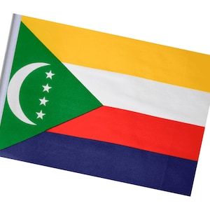 May include: A Comoros flag, featuring a green triangle with a white crescent and four stars, yellow, white, red, and blue stripes. The flag is rectangular and mounted on a white pole. The flag is a symbol of national identity.
