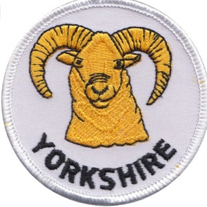 May include: A white embroidered patch featuring a yellow ram's head and the word "YORKSHIRE" in black lettering.