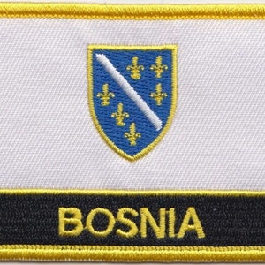 May include: A white embroidered patch with a blue shield and yellow trim. The shield has a white diagonal line and five yellow fleurs-de-lis. The word "BOSNIA" is embroidered in yellow on a black background below the shield.