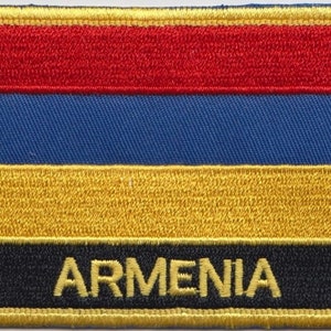 Peut inclure: Un écusson brodé aux couleurs rouge, bleu, orange et noir avec l'inscription "ARMENIA" en lettres jaunes.