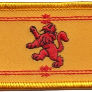 May include: A yellow embroidered patch featuring a red lion rampant, the national symbol of Scotland. The patch has a red border and a gold border.