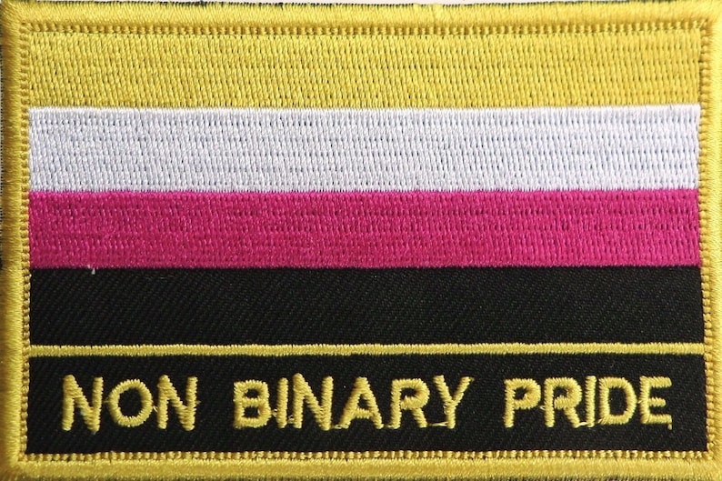 K&ouml;nnte beinhalten: Ein gestickter Aufn&auml;her in Gelb, Wei&szlig;, Rosa und Schwarz mit dem Text "NON BINARY PRIDE" in Gelb.