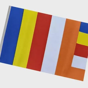 Op de afbeelding: Een rechthoekige vlag met verticale strepen in blauw, geel, rood, wit en oranje. Een kleiner gedeelte aan de rechterkant heeft blauwe, gele, rode en witte strepen. De vlag is waarschijnlijk een religieus of cultureel symbool.
