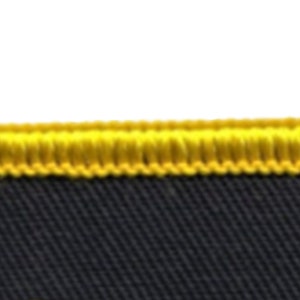 May include: Close-up of a black fabric with a yellow stitched border.