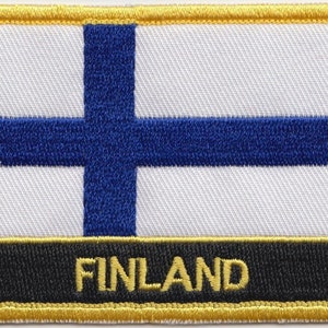Op de afbeelding: Een blauw en wit Fins vlagpatch met een gouden rand en het woord "FINLAND" in gouden letters op een zwarte achtergrond.