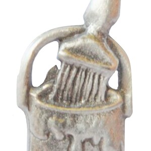 Könnte beinhalten: Eine silberne Farbdose mit einem Pinsel, der aus der Oberseite herausragt. Die Farbdose hat einen Griff und einen Farbklecks an der Seite.