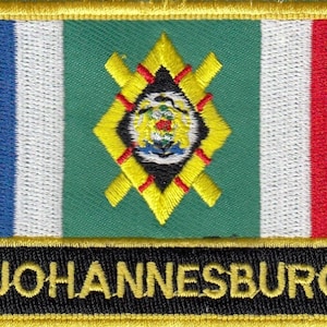 May include: A gold embroidered patch featuring a green, white and red flag with a yellow diamond-shaped emblem in the centre. The text "JOHANNESBURG" is embroidered in gold on a black background.