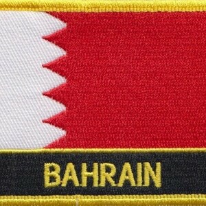 May include: An embroidered patch featuring the flag of Bahrain, with a red and white design and a yellow border. The word "BAHRAIN" is embroidered in yellow on a black background.