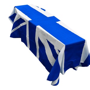 Könnte beinhalten: Eine blaue und weiße Tischdecke mit einem Design, das an die finnische Flagge erinnert. Die Tischdecke ist über einen Tisch gelegt und hat einen blauen Hintergrund mit einem weißen Kreuz in der Mitte.