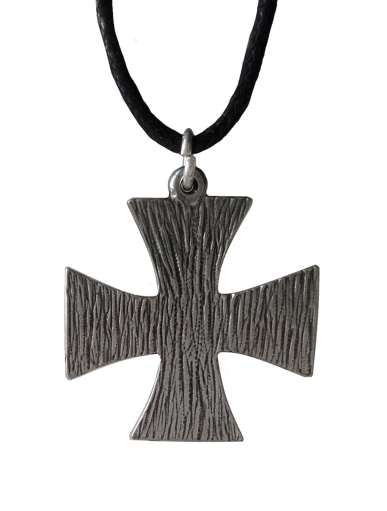May include: A silver cross pendant with a textured surface, hanging from a black cord.