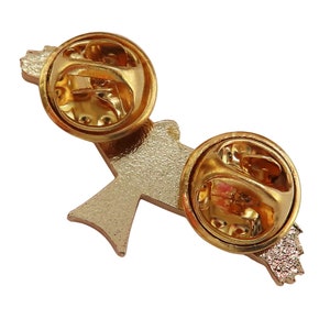 May include: Gold-tone metal pin with a stylized bird design. The back of the pin has two butterfly clasps.