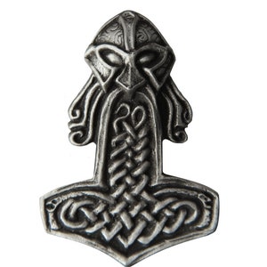 Könnte beinhalten: Ein silberner Anhänger in Form eines Wikinger-Hammers, Mjolnir, mit einem detaillierten Design eines Kriegerkopfes mit Bart und Helm.