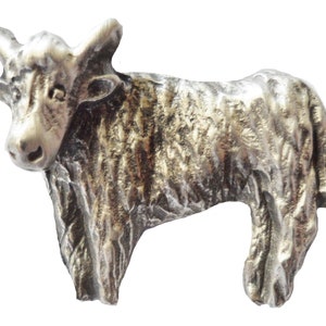 Puede incluir: Una figurita de peltre de color plateado de un toro peludo y peludo con una cara y cuernos detallados.