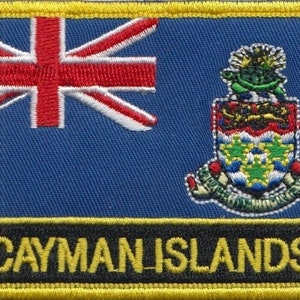 Op de afbeelding: Een geborduurde patch met de vlag van de Kaaimaneilanden, met een blauwe achtergrond, een Union Jack in de linkerbovenhoek en een wapenschild aan de rechterkant. De tekst "CAYMAN ISLANDS" is in geel op een zwarte achtergrond geborduurd.