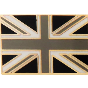 May include: A rectangular pin featuring the Union Jack flag design. The flag has a gold border, with black, white, and gray sections. The pin is a decorative accessory.