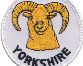 May include: A white embroidered patch with a yellow ram's head and the word "YORKSHIRE" in black lettering.
