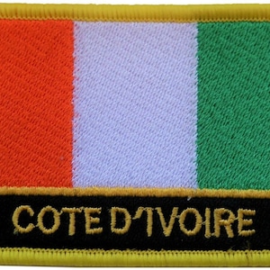 Op de afbeelding: Een stoffen patch met de vlag van Ivoorkust. De vlag is oranje, wit en groen met de woorden "Côte d'Ivoire" in gouden letters op een zwarte achtergrond.