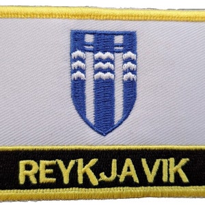 Könnte beinhalten: Ein gestickter Aufnäher in Gelb und Schwarz mit dem Städtenamen "REYKJAVIK" und einem blauen und weißen Wappen.