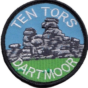 May include: Embroidered patch with a blue background and white text that reads "Ten Tors Dartmoor". The patch features a gray embroidered image of a rock formation.