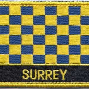 May include: A yellow and blue checkered patch with the word "SURREY" in yellow lettering on a black background.