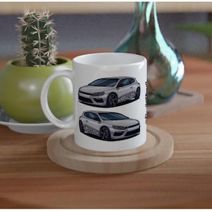 May include: White ceramic mug featuring two illustrations of a silver car. The car illustrations have black wheels and are labeled with text. The mug sits on a wooden coaster. A green cactus and a decorative vase are in the background.