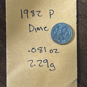 Puede incluir: Una moneda de diez centavos de 1982 P sobre un sobre de color beige. El sobre tiene texto escrito a mano que dice "1982 P Dime .081 oz 2.29g". La moneda es de color plateado y tiene las palabras "UNITED STATES OF AMERICA" y "ONE DIME".
