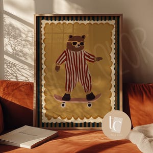 May include: Framed art print featuring a bear in sunglasses and a striped jumpsuit skateboarding. The artwork has a yellow background with a scalloped edge, set in a wooden frame. The print is displayed on a burnt orange couch.