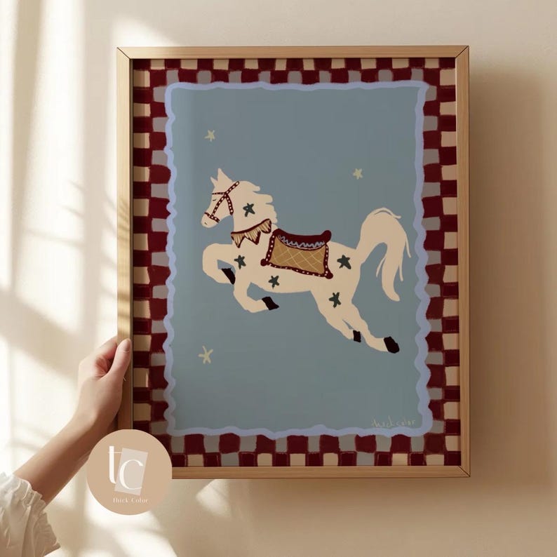 May include: A framed art print featuring a whimsical illustration of a white horse with a saddle and star accents against a light blue background. The artwork is framed with a gold-colored border and a red and white checkered pattern.
