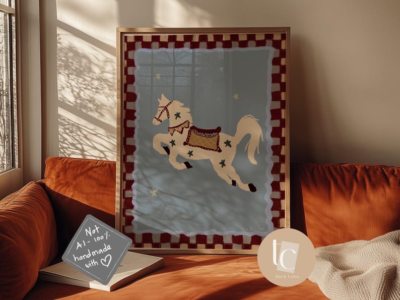 May include: A framed art print featuring a whimsical illustration of a carousel horse. The horse is cream-colored with a decorative saddle and star accents, set against a light blue background. The frame has a red and white checkered border.