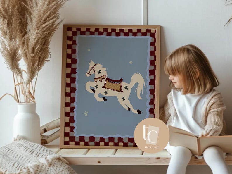 May include: A framed art print featuring a cream-colored carousel horse with a decorative saddle and bridle, set against a light blue background. The frame has a red and white checkered border. Decorative stars are scattered around the horse.