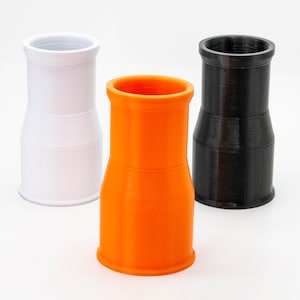 Op de afbeelding: Drie plastic buizen, een witte, een oranje en een zwarte. De buizen zijn allemaal even groot en even gevormd, en ze staan allemaal rechtop op een wit oppervlak.
