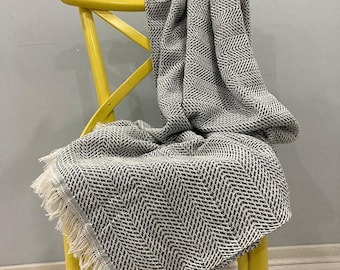 May include: A black and white chevron patterned throw blanket with fringe on a yellow chair.