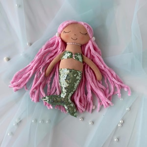 May include: A handmade mermaid doll with long pink yarn hair, a green sequin tail, and a pink seashell bikini top.