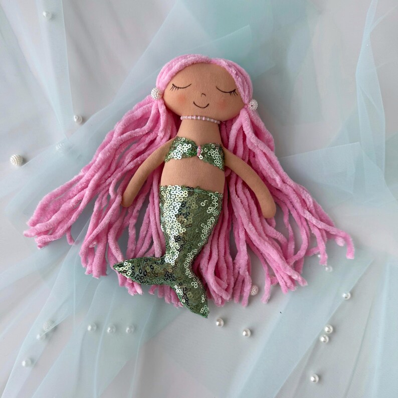 May include: A handmade mermaid doll with long pink yarn hair, a green sequin tail, and a pink seashell bikini top.