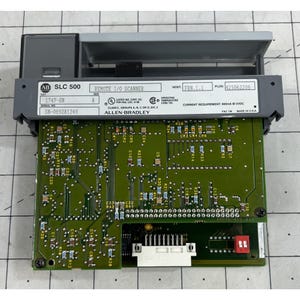 Könnte beinhalten: Ein Allen-Bradley SLC 500 Remote I/O Scanner. Das Gerät hat eine grüne Leiterplatte mit verschiedenen Komponenten und einen grauen Deckel. Text auf dem Gerät enthält "1747-SN", "SN-0892A1249" und "FRN.1.1". Das Gerät ist mit "Made in USA" gekennzeichnet.