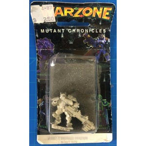 Puede incluir: Figura en miniatura Bauhaus Dragoon de color plateado de la serie Mutant Chronicles, empaquetada en un blíster transparente. El embalaje presenta el logotipo "ARZONE" y el texto "MUTANT CHRONICLES". La figura está etiquetada como #9867-A.
