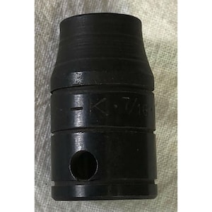 Puede incluir: Una herramienta de metal negro con forma cilíndrica y una parte superior ensanchada. La herramienta tiene un agujero en el lateral y el texto "-K 7/16" es visible. La herramienta parece ser utilizada para fines mecánicos.