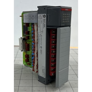May include: A gray Allen-Bradley SLC 500 input module with a red "INPUT" section. The module has a series of numbered input ports and a label with model and serial numbers. A green circuit board is attached.