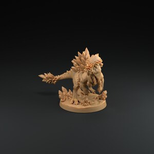 Peut inclure: Une figurine miniature d'un dinosaure brun recouvert de cristaux, avec un dos et une queue hérissés d'épines. Le dinosaure est debout sur une base ronde avec une surface texturée.