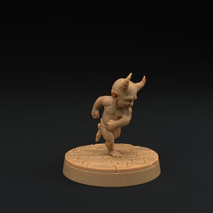 Puede incluir: Una pequeña figura esculpida en marrón de una criatura cornuda con un cuerpo humanoide. La criatura está de pie sobre una base redonda y marrón con una superficie texturizada.