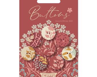May include: A pack of eight assorted fabric buttons with floral patterns in shades of pink, red, and cream. The buttons are arranged in a circle on a red background with a floral design. The text "Buttons" and "Autumn/Winter 2024" is printed on the card. The Tilda logo is at the bottom of the card.