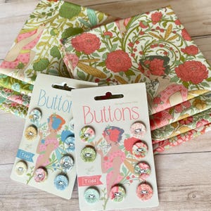 May include: Two packs of "Buttons" with floral fabric buttons and stacks of floral fabric. The button packaging features a woman in a pink dress. The fabric has a floral pattern with pink, green, and yellow accents.