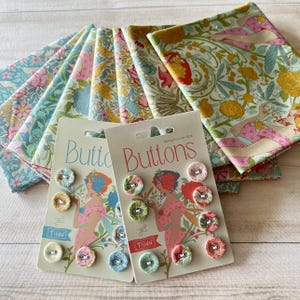 Pode incluir: Uma coleção de quadrados de tecido floral e dois cartões de botões da marca Tilda. Os botões são cobertos com tecido com estampas florais. Os quadrados de tecido são em várias cores pastel com desenhos florais. Os cartões têm uma ilustração de mulher.