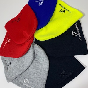May include: Six beanies in different colors, including red, blue, yellow, black, gray, and white. Each beanie has the same logo embroidered on it, which says "LIVE THRU MOMENTS" and features a crown.