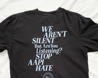 May include: Black t-shirt with a light blue graphic print that reads "WE AREN'T SILENT But Are You Listening? STOP AAPI HATE". The graphic also includes a small circle with the text "LN DESIGNS MAKE A STATEMENT YOUR VOICE MATTERS".